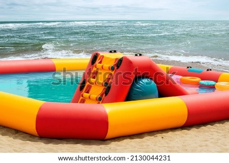 Large inflatable pool on the beach of the sea with water and a slide for children's entertainment