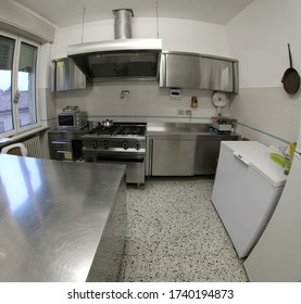 large interior of industrial kitchen with stainless steel stove and large extractor hood without cooks