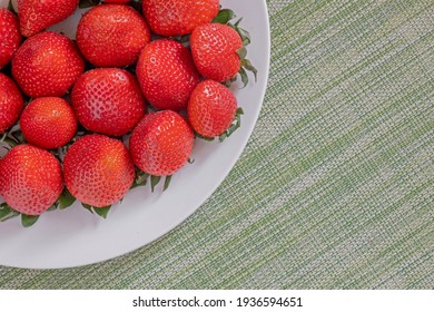 large juicy strawberries on a plate, red berries on the table, summertime for natural vitamins, place for text