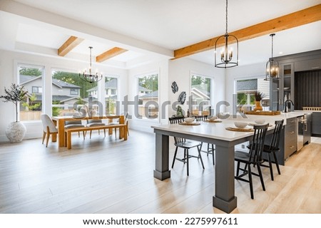large kitchen with beamed ceiling hardwood floors white countertop grey cabinets and set dining table with large windows bar cart view to living room