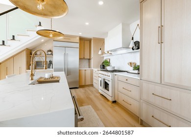 Large kitchen dining room interior white marble countertops brass light fixtures modern oven and stainless steel appliance ocean view floor to ceiling windows hardwood floor modern spacious design