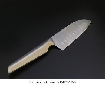 A large kitchen knife on a dark background. Knife with a wide shar blade isolated on black background. Unused professional chef knife. Cutting utensils. Chef knife. Kitchen utensils isolated.