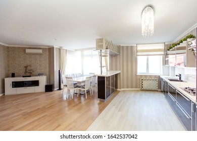 Large kitchen-living room in classic style and beige houses in the cottage. Black and white kitchen, beige Wallpaper with a pattern, bar counter, white table with chairs, wooden floors. - Shutterstock ID 1642537042