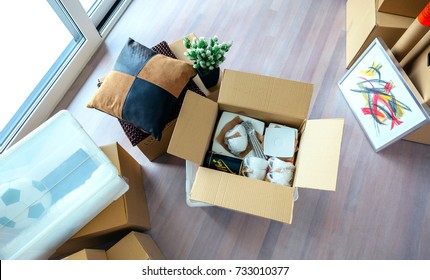 Large Living Room With Stack Of Moving Boxes And Open Kitchenware Box