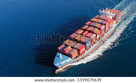 Large loaded Container Ship roaring across the open sea, Aerial view.