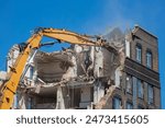 Large long armed demolition machine seen demolishing a building.