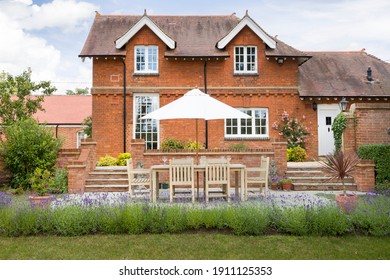 Large Luxury Detached House And Garden In UK With Garden Furniture On A Patio In Summer