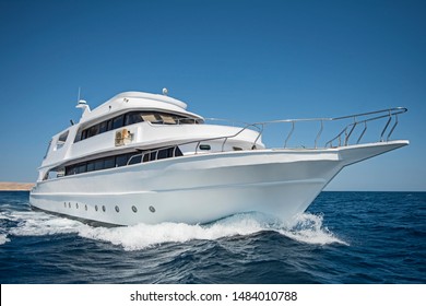 Large luxury motor yacht under way sailing out on tropical sea ocean with blue sky background