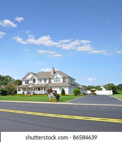 Large Luxury Two Car Garage Suburban McMansion Style Home In Residential Neighborhood With Garage Sale Sign Next To Mailbox On Sunny Blue Sky Day