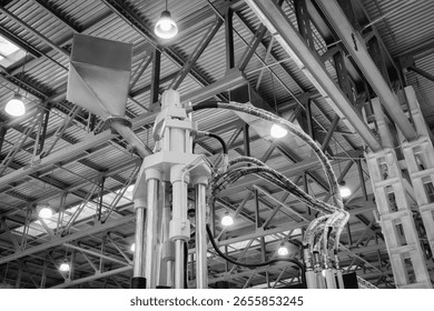 Large machine with a white base and a black hose. The machine is in a large building with many lights.