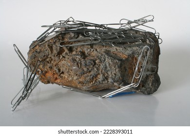 Large magnetite sample with paper clips attracted and covering the sample - Shutterstock ID 2228393011