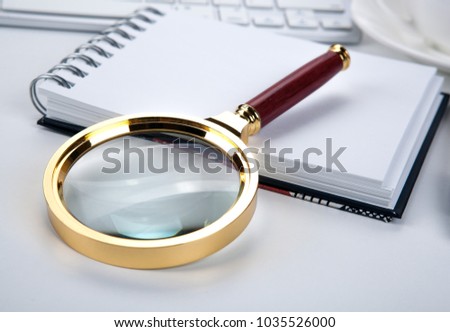 large magnifying glass lies on a notebook on the desktop