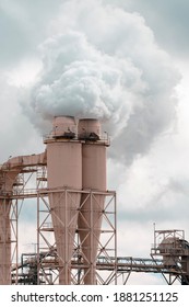 A Large Manufacturing Facility In A Regional Township With Steam Coming From The Chimney Stacks During Processing