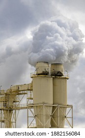 A Large Manufacturing Facility In A Regional Township With Steam Coming From The Chimney Stacks During Processing