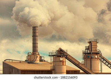 A Large Manufacturing Facility In A Regional Township With Steam Coming From The Chimney Stacks During Processing