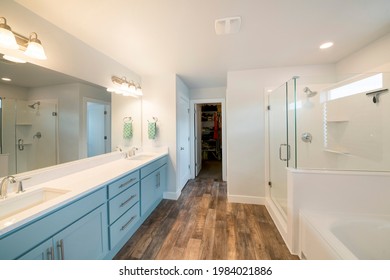 Large Master Bathroom Interior With Walk In Closet. There Is A Double Vanity Sink With Mirror On The Wall And Towel Hanging On Side Across The Shower With Glass Enclosure And Window Near The Tub.