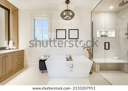 Large master ensuite bathroom with free standing tub glass shower wooden cabinets and white tile