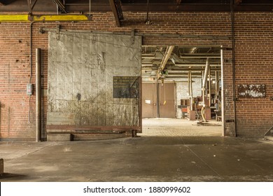 Large Metal Barn Door Left Open In The Basement Level Of An Abandoned Factory In The Deep South