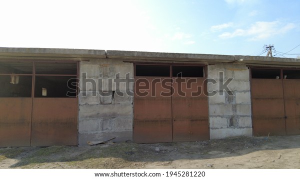 large metal gates. rusty old gate. Old warehouse,\
industrial building, exerier. Old, metal gates for cars to enter.\
front view. padlock