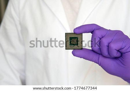 Large microchip (microprocessor) demonstrated by scientist in gloves and a white lab coat. Copy space. 