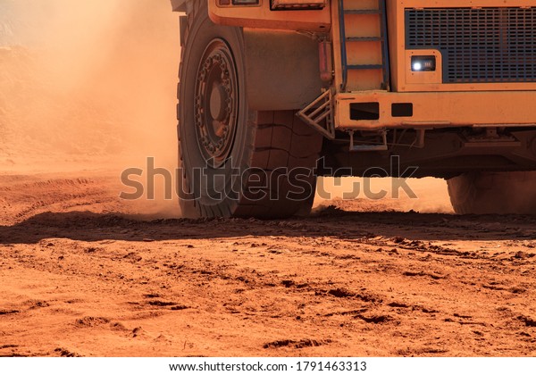 Large
mining dump truck lifts orange dust on
wheels