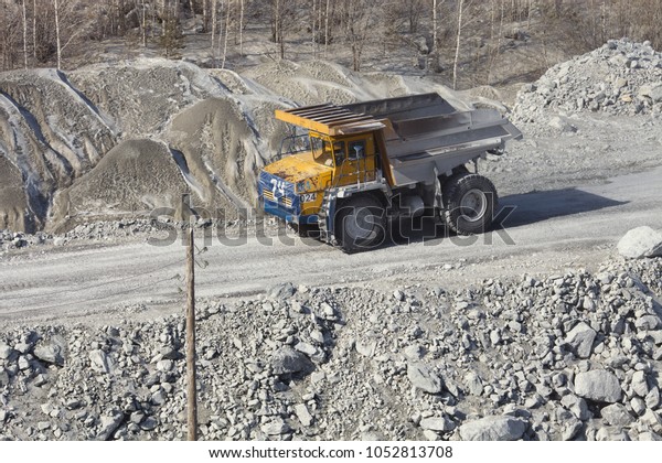 Large mining truck rides along the road\
against a backdrop of rock placers in a quarry. Mining industry.\
Quarry mining equipment.