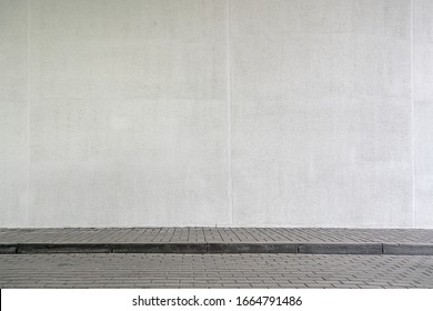 large modern building with high white wall near empty sidewalk covered with grey stone tiles on city street in spring - Shutterstock ID 1664791486
