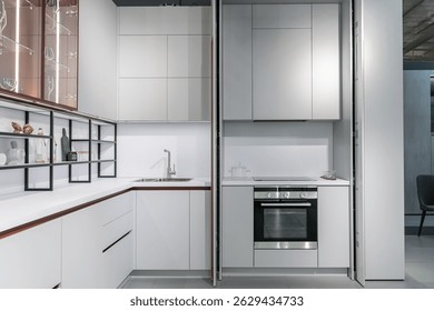 Grande cocina moderna empotrada con muchos armarios superiores e inferiores, cajones y estantes. encimera ligera, electrodomésticos empotrados, puertas de vidrio, grifo y fregadero.