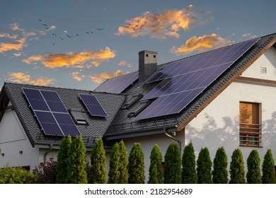 Large modern house with solar panels on a pitched roof. Natural light at sunset. Blue solar panels. - Shutterstock ID 2182954689