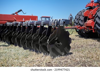 Large modern plow or disc harrow for cultivating the land. Tractor plows a piece of land in a field.