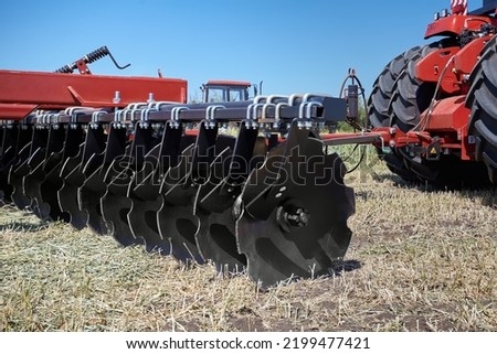 Large modern plow or disc harrow for cultivating the land. Tractor plows a piece of land in a field. Foto d'archivio © 