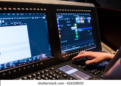 Large modern show light controller with screens and operators hand and ajusted presets - close up photo
