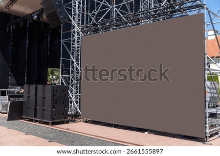 A large modular LED screen displays vibrant video footage during an energetic outdoor concert, illuminating the night with dynamic visuals.