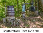 Large moonshine still set up hidden in an over grown area of the forest with glass jars and jugs on the ground closeup view