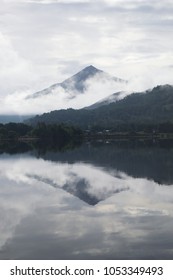 Large mountain and clouds reflected into a lake.