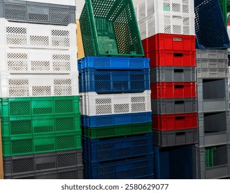 Large multi-colored plastic boxes for goods and products stand as a wall in a warehouse.