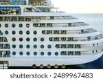 Large multi-deck cruise ship side view fragment with round portholes rows and cabins balconies with railing