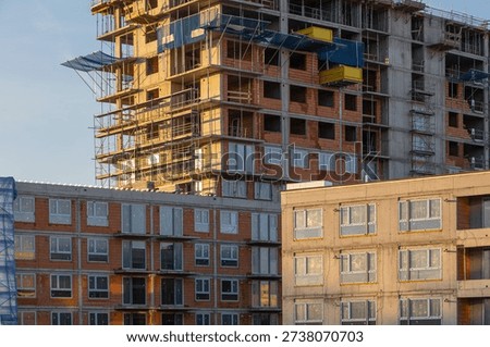 large multi-story building features exposed brickwork and concrete framing. Scaffolding, safety netting, and blue protective mesh