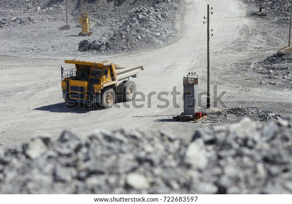 Large multi-toned yellow mining truck is\
traveling in a quarry.