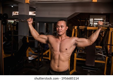 A Large And Muscular Asian Man Does Standing Double Bicep Cable Curls At A Hardcore Gym. Working Out Bicep Intensely.