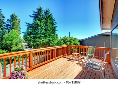 Large New Wood Deck Home Exterior With Chairs, Trees And Flowers.