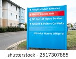 Large, NHS type information sign showing outpatients department, out of hours doctors and a minor injury unit. located at the entrance to the large hospital campus.