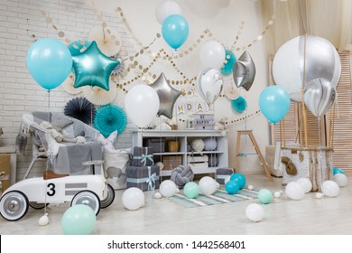 A large number of color balloons. Birthday teal and silver decorations with gifts, toys, garlands and balloon for yearling little baby party on a white playroom background.