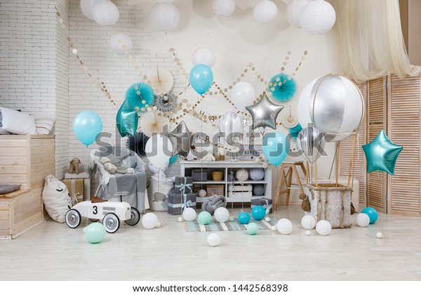 A large\
number of color balloons. Birthday teal and silver decorations with\
gifts, toys, garlands and balloon for yearling little baby party on\
a white playroom background.