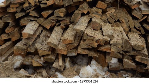 A Large Number Of Materials From Natural Wood, Sawdust, Lies Under The Open Sky Covered With White Snow.