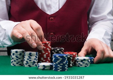 a large number of multi-colored chips for playing in a casino for money, for large bets, on the background of a red vest