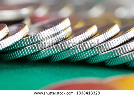 a large number of silver-colored metal coins stacked together on a green background, legal tender that is used for payments in the state, beautiful coins close-up the same coin value foreign currency