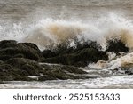 Large ocean wave crashing over rocks on shoreline