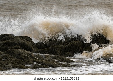 Large ocean wave crashing over rocks on shoreline - Powered by Shutterstock