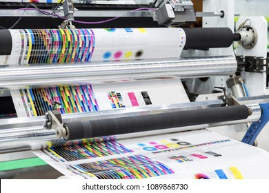 Large offset printing press or magazine running a long roll off paper in production line of industrial printer machine.